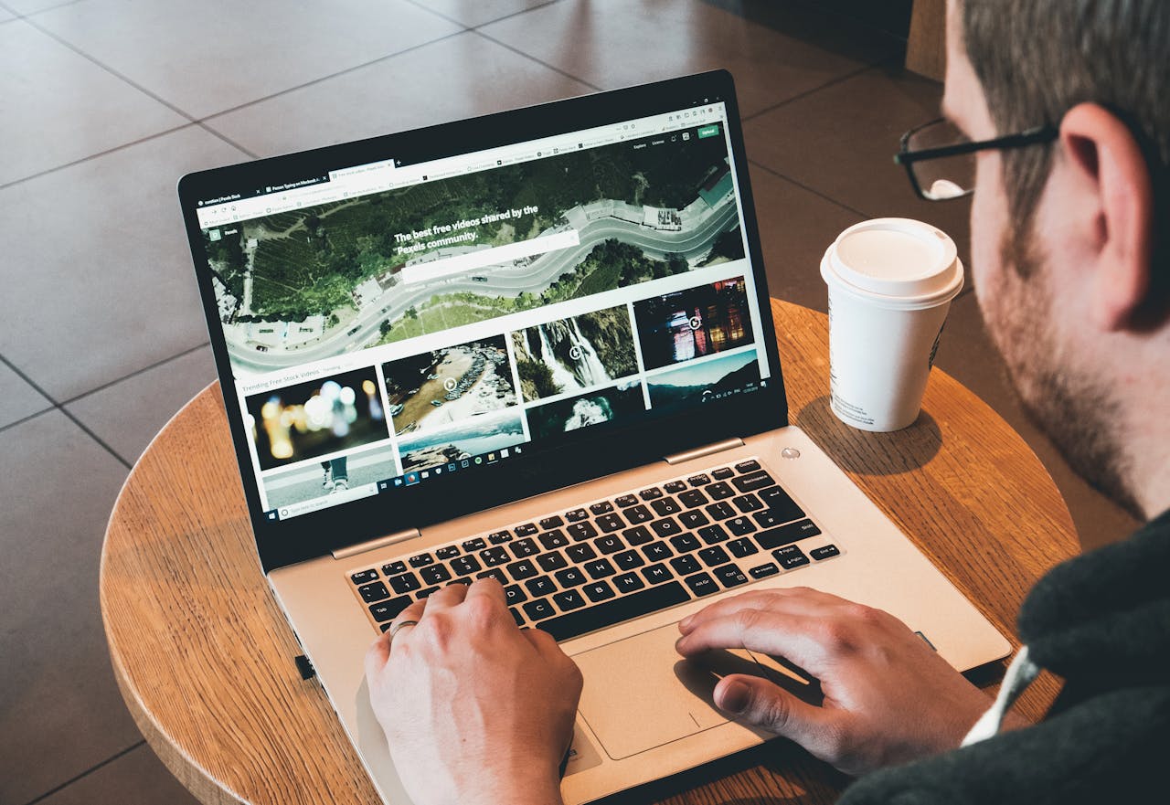 Services Man working on a laptop in a modern workspace with a coffee cup nearby, showcasing online activity.